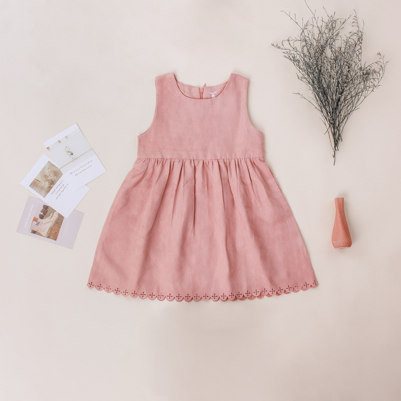 Trendy dress for girl near postcards on beige background